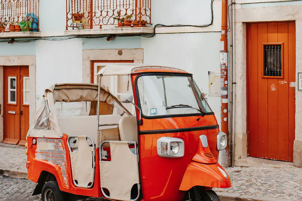 Red tuk-tuk in an alley in Lisbon